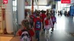 Grupa dzieci idzie w parach przez hol lotnisku