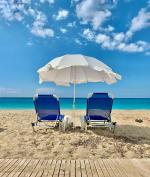 Parasol i dwa leżaki na plaży nad brzegiem morza